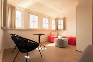 Een moderne kamer met een zwarte stoel, een klein tafeltje en rode zitzakken.