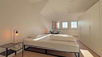 Een moderne slaapkamer met een bed, nachtkastje, lamp en uitzicht op de stad door ramen.