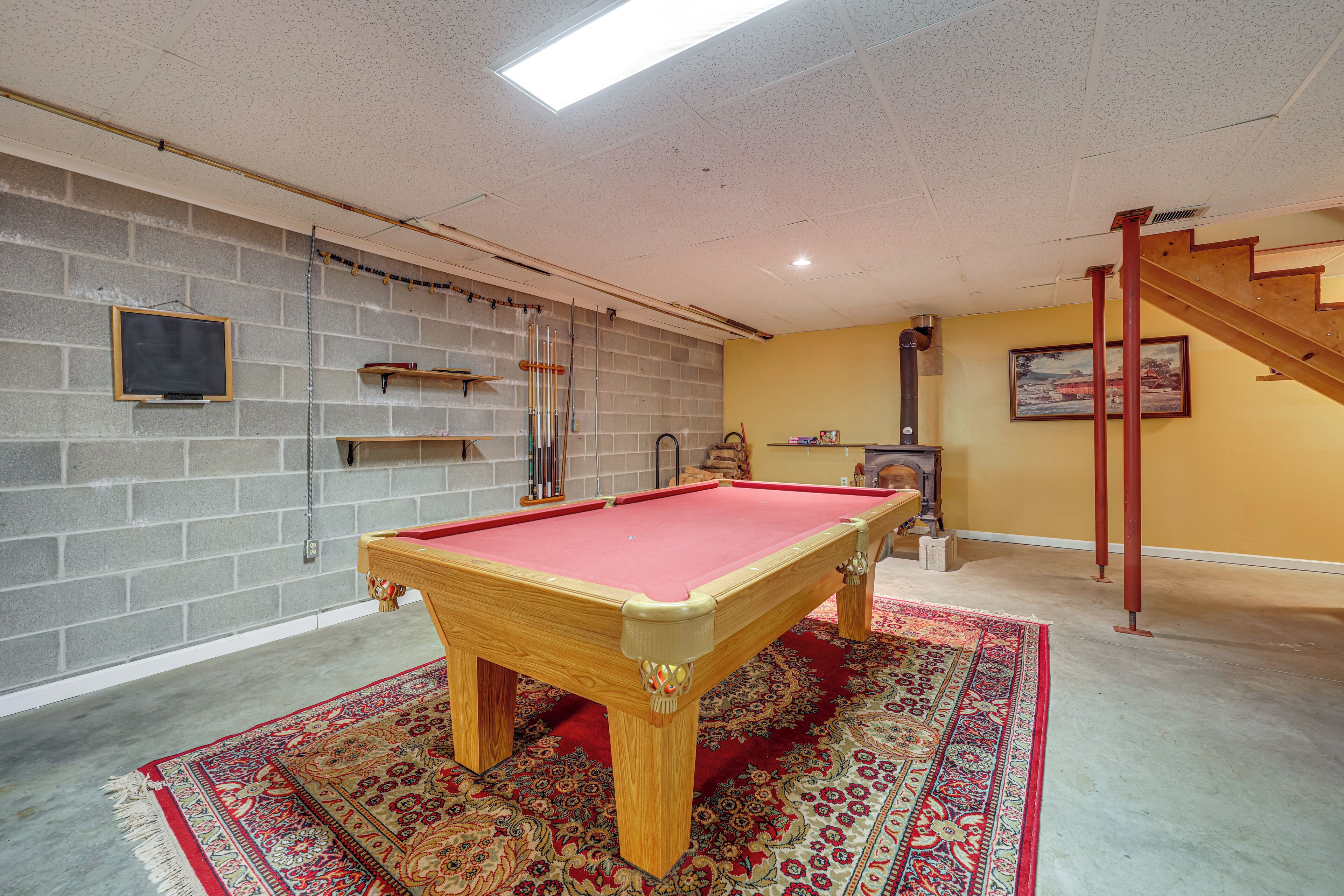 Ein Billardtisch in einem Raum mit Backsteinwand, einer Treppe und einem Kamin.