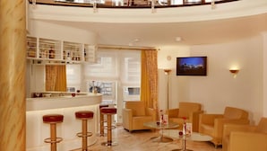 A modern hotel lobby with a curved bar, seating area, and a television on the wall. - Sunday Hotel Stade Widukind Single Room (Stade)