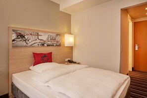A hotel room with a bed, a nightstand, a telephone, and a painting on the wall. - Sunday Hotel Stade Widukind Single Room (Stade)