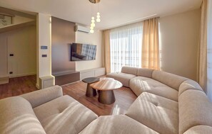 A modern living room with a sectional sofa, a round coffee table, and a flat-screen TV mounted on the wall. - Awesome home in Drace with sauna (Drace)