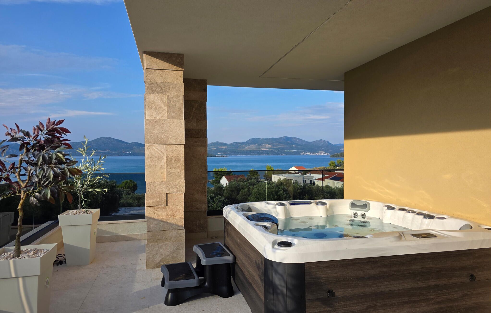 A hot tub on a balcony with a view of the sea and mountains.