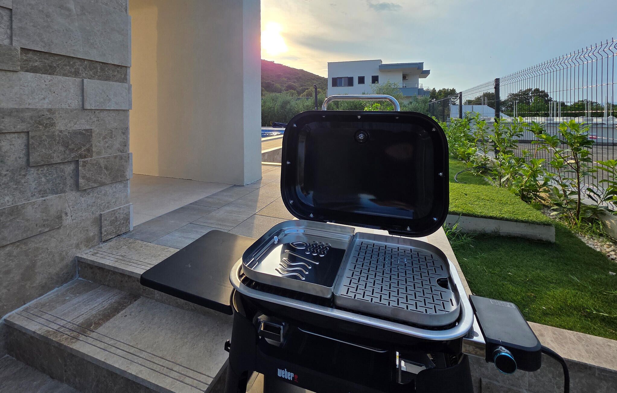 Ein tragbarer Grill mit einer Tastatur auf einer Terrasse mit Stufen, die zu einem Gebäude führen.