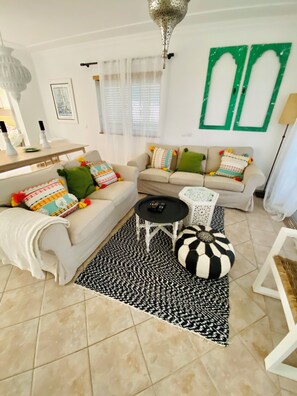 A living room with a sofa, a coffee table, and a patterned rug. - Villa Med - private pool, garden, barbecue, air conditioning, and ocean view (Olhos de Água)
