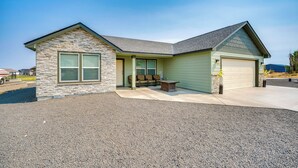 Une maison à deux étages avec une façade en pierre, un garage et un patio couvert.