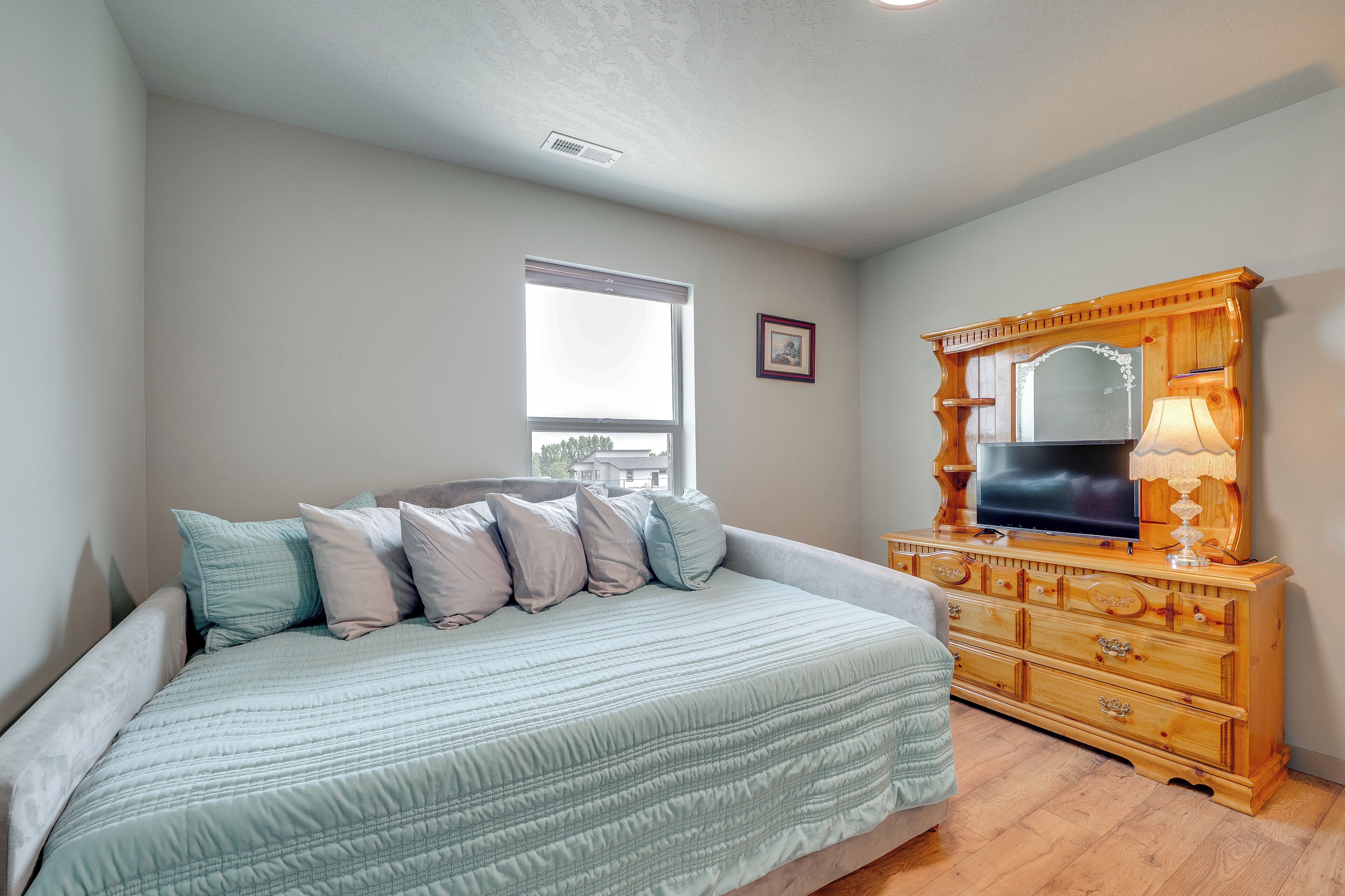 Un dormitorio con cama, cómoda y ventana.