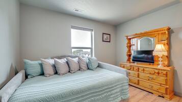 Un dormitorio con cama, cómoda y ventana.