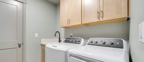 A laundry room with a washing machine, dryer, and a sink.