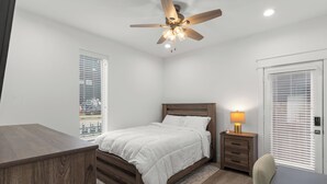 A bedroom with a bed, bedside table, lamp, and a ceiling fan. - Luxurious 3-Bedroom Home In Downtown Houston Area (Houston)