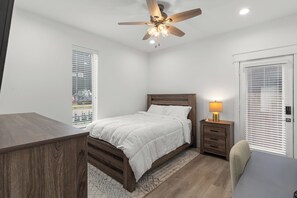 Ein Schlafzimmer mit einem Bett, einem Nachttisch, einer Lampe und einem Deckenventilator.