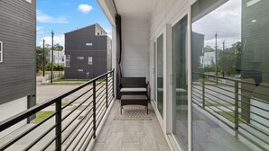 A balcony with a metal railing, a bench, and a view of neighboring buildings. - Luxurious 3-Bedroom Home In Downtown Houston Area (Houston)