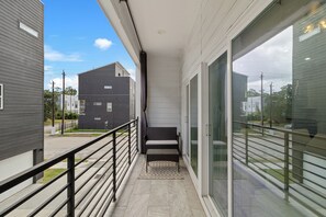 Ein Balkon mit Metallgeländer, einer Sitzbank und Blick auf benachbarte Gebäude.