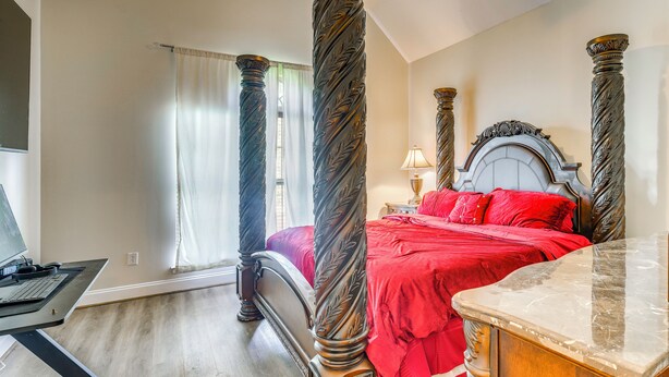 Una camera da letto con un letto a baldacchino, una scrivania con un computer e un comodino in marmo.