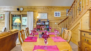 Un intérieur en bois avec une table à manger dressée pour six personnes, entourée de chaises en bois.