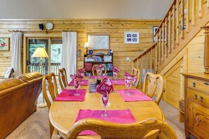 Interior de madeira com uma mesa de jantar posta para seis pessoas, rodeada por cadeiras de madeira.