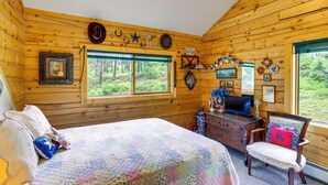 Une chambre de style cabane, équipée d’un lit, d’une commode, d’un téléviseur et de divers éléments de décoration.