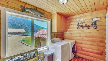 A cabin interior with a large window, a washing machine, and a bench.