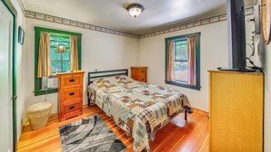 Ein Schlafzimmer mit Bett, Schminktisch und Fernseher auf einem Schrank.