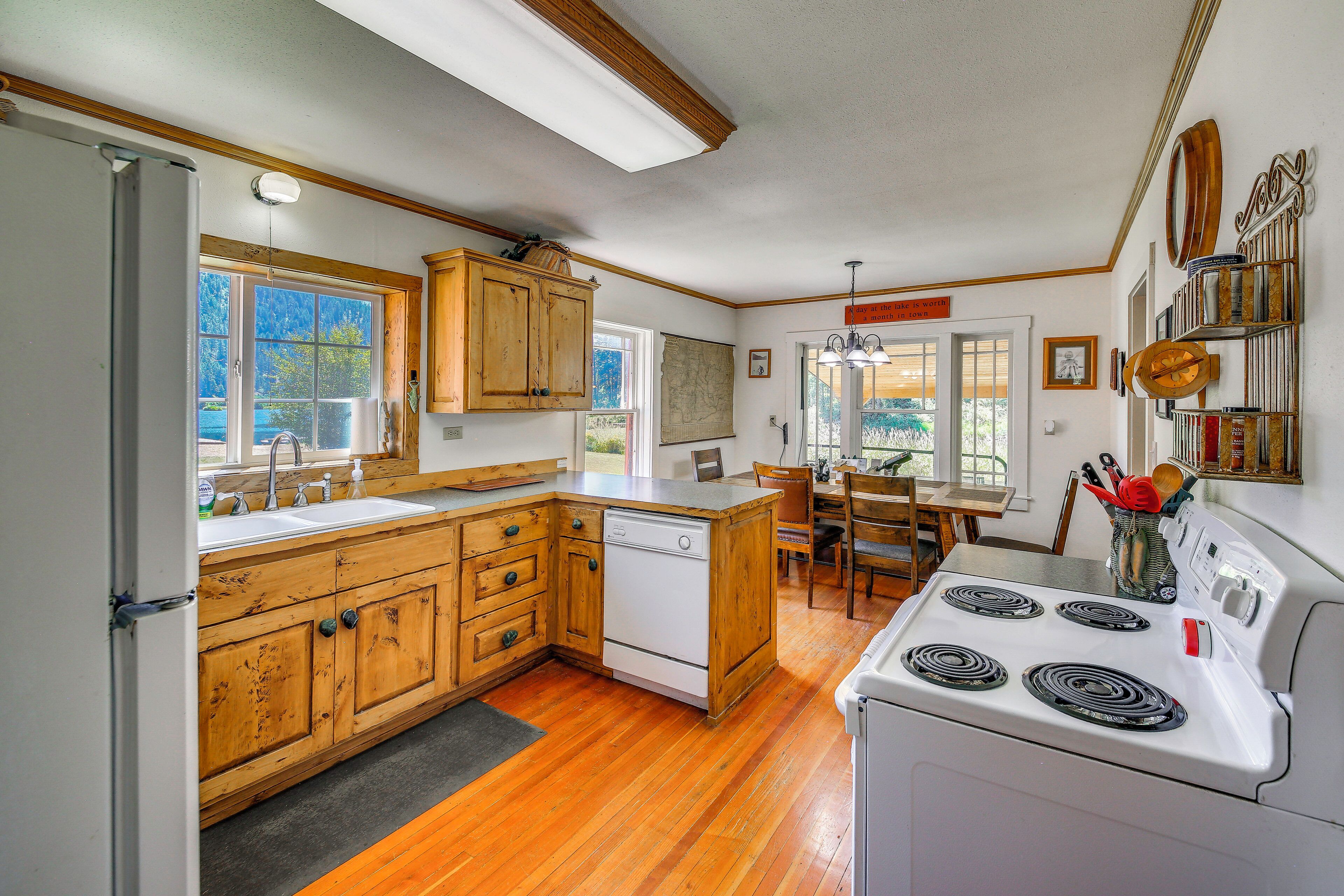 A kitchen with wooden cabinets, a white stove, and a dining area with a table and chairs.