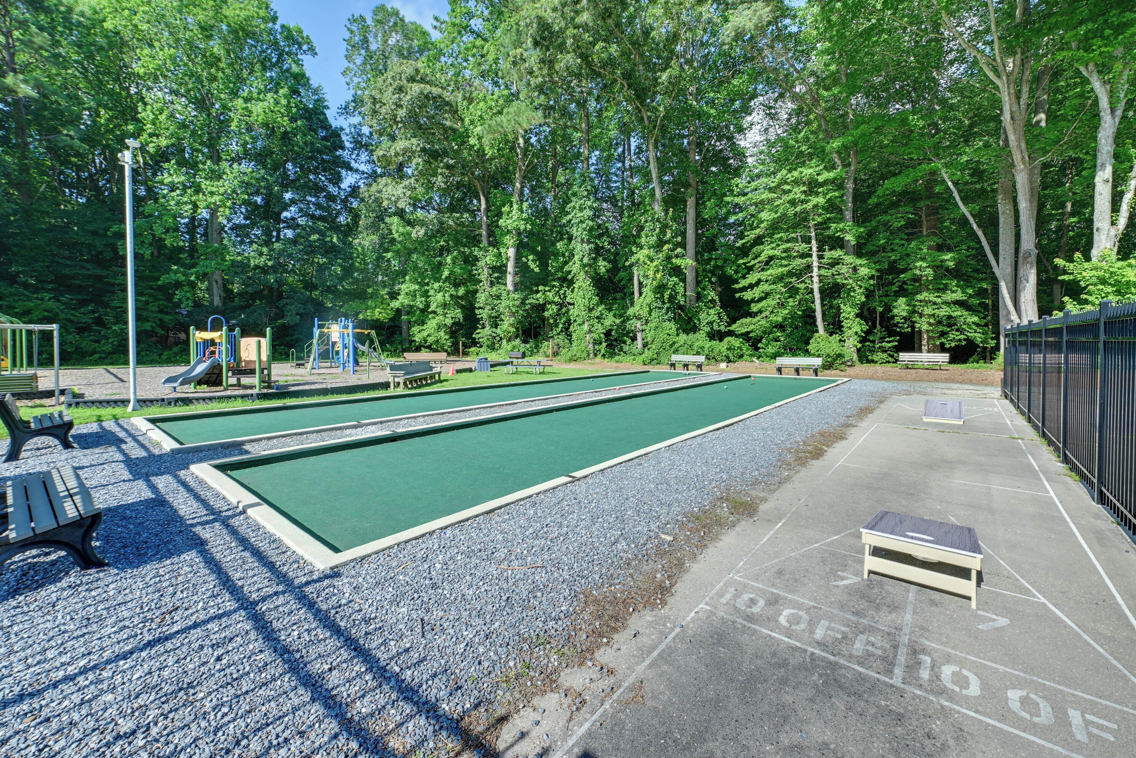 A pool area with a green pool, a playground, and benches.