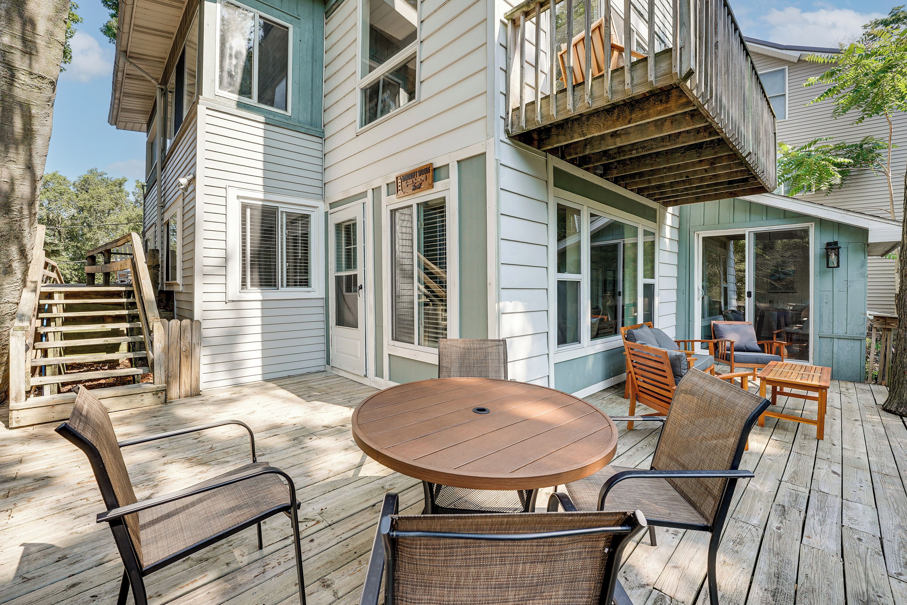 A deck with outdoor furniture, a wooden table, and chairs.