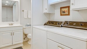 A laundry room with a washing machine, a dryer, and a mirror above the sink.