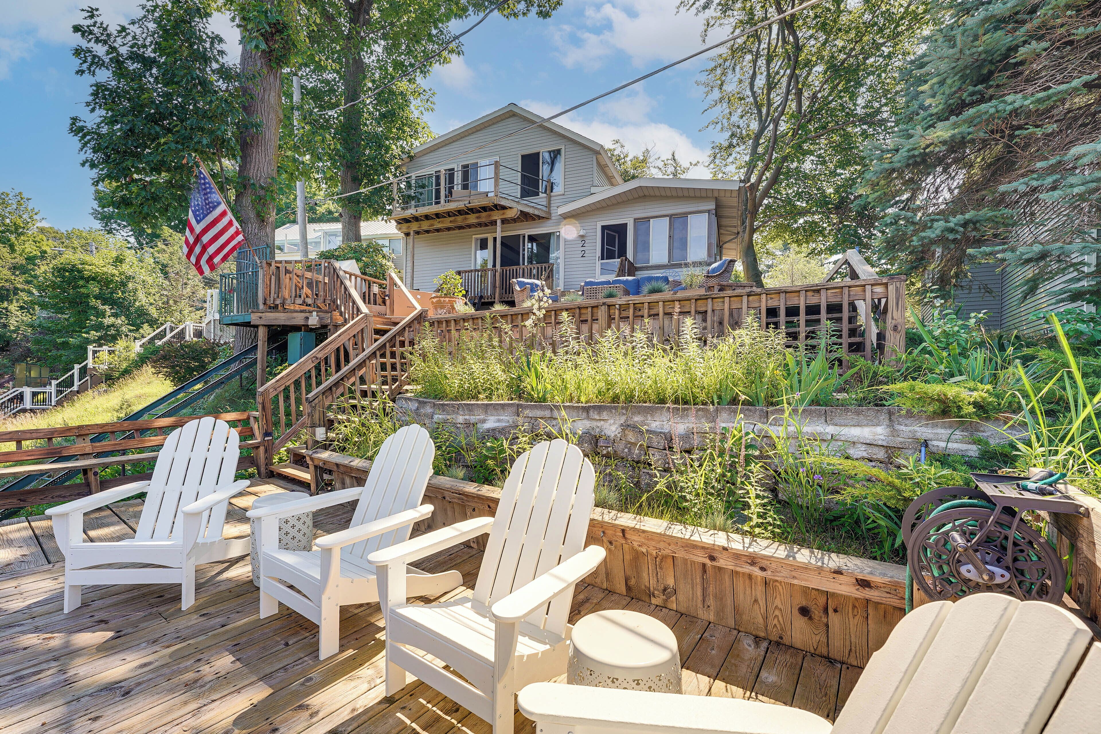 Ein Wohnhaus mit Holzterrasse, Sitzgelegenheiten im Freien und einem Balkon.