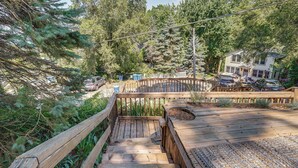 A wooden staircase leading to a deck with a view of a house and surrounding trees.
