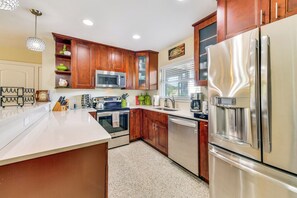 A modern kitchen with stainless steel appliances, wooden cabinets, and a granite countertop. - Walk to Park & Pool: Sarasota Family Home w/ Yard (Sarasota)