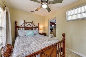 Ein Schlafzimmer mit einem hölzernen Himmelbett, einem Deckenventilator und Blick auf die Küche durch eine offene Tür.