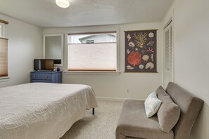 Ein Schlafzimmer mit Bett, Schminktisch, Sessel, Fenster und Wandbild.