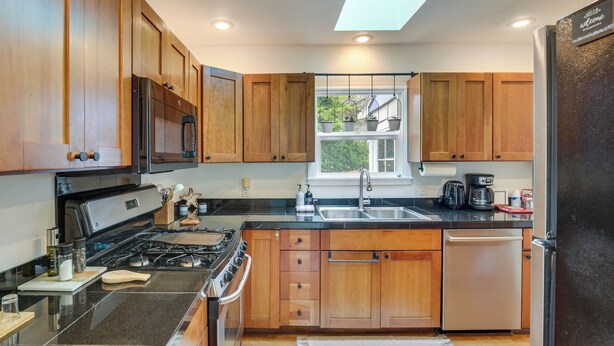 A modern kitchen with wooden cabinets, a stainless steel stove, and a built-in dishwasher. - Walk to Beaches! Lincoln City Family Home w/ Yard (Lincoln City)