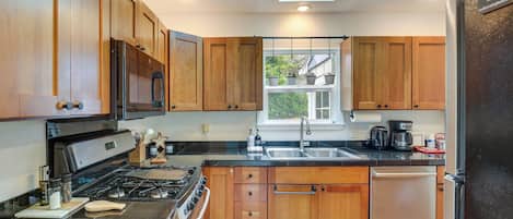 A modern kitchen with wooden cabinets, a stainless steel stove, and a built-in dishwasher.