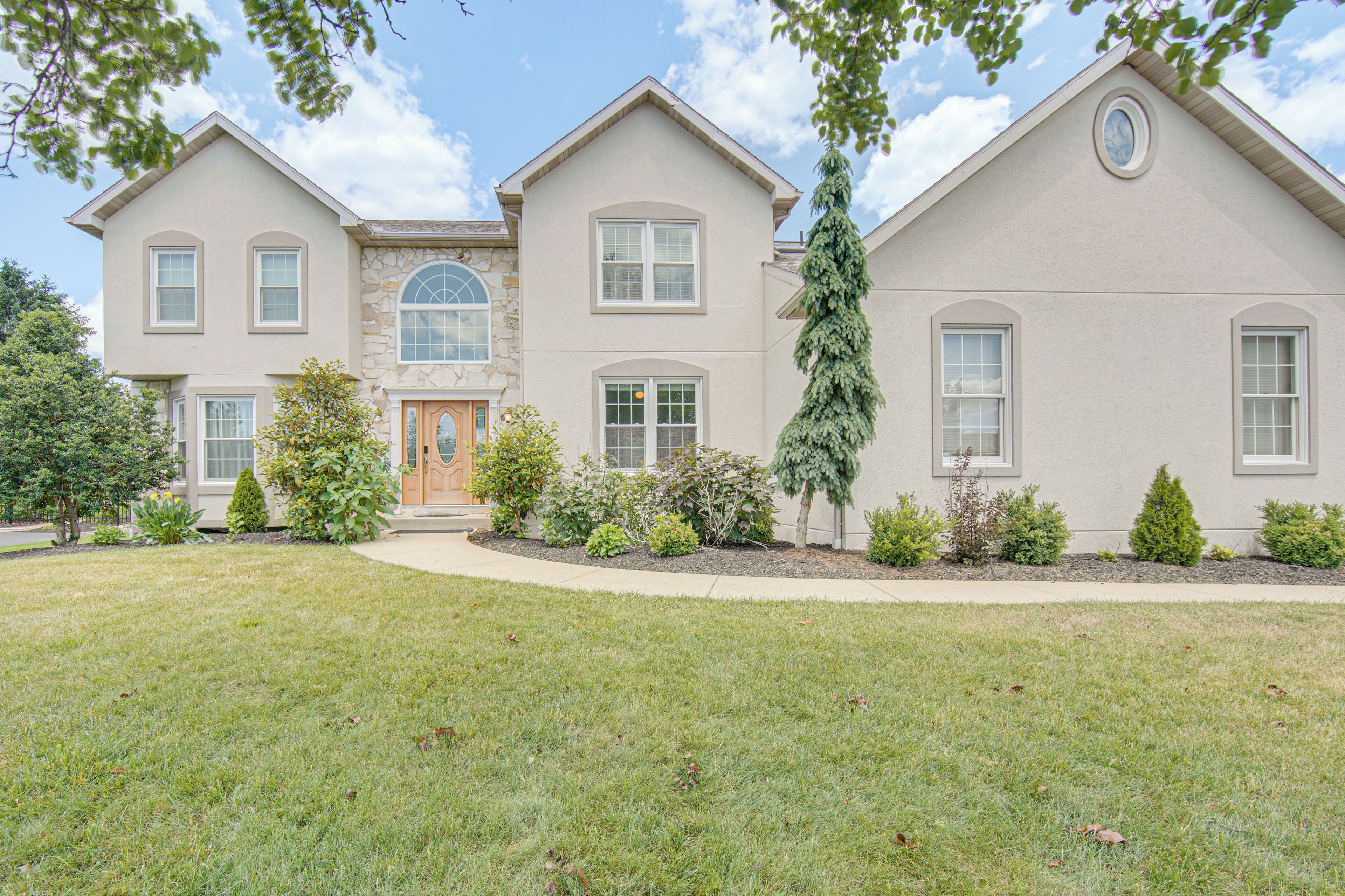 A two-story house with a stone facade, a large front door, and a well-maintained lawn.