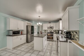 A modern kitchen with white cabinetry, stainless steel appliances, and a tiled floor. - Spacious Sinking Spring Home w/ Outdoor Oasis! (Sinking Spring)