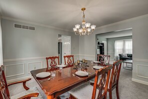 A dining room with a wooden table set for six, surrounded by chairs, a chandelier, and a view into a living area. - Spacious Sinking Spring Home w/ Outdoor Oasis! (Sinking Spring)