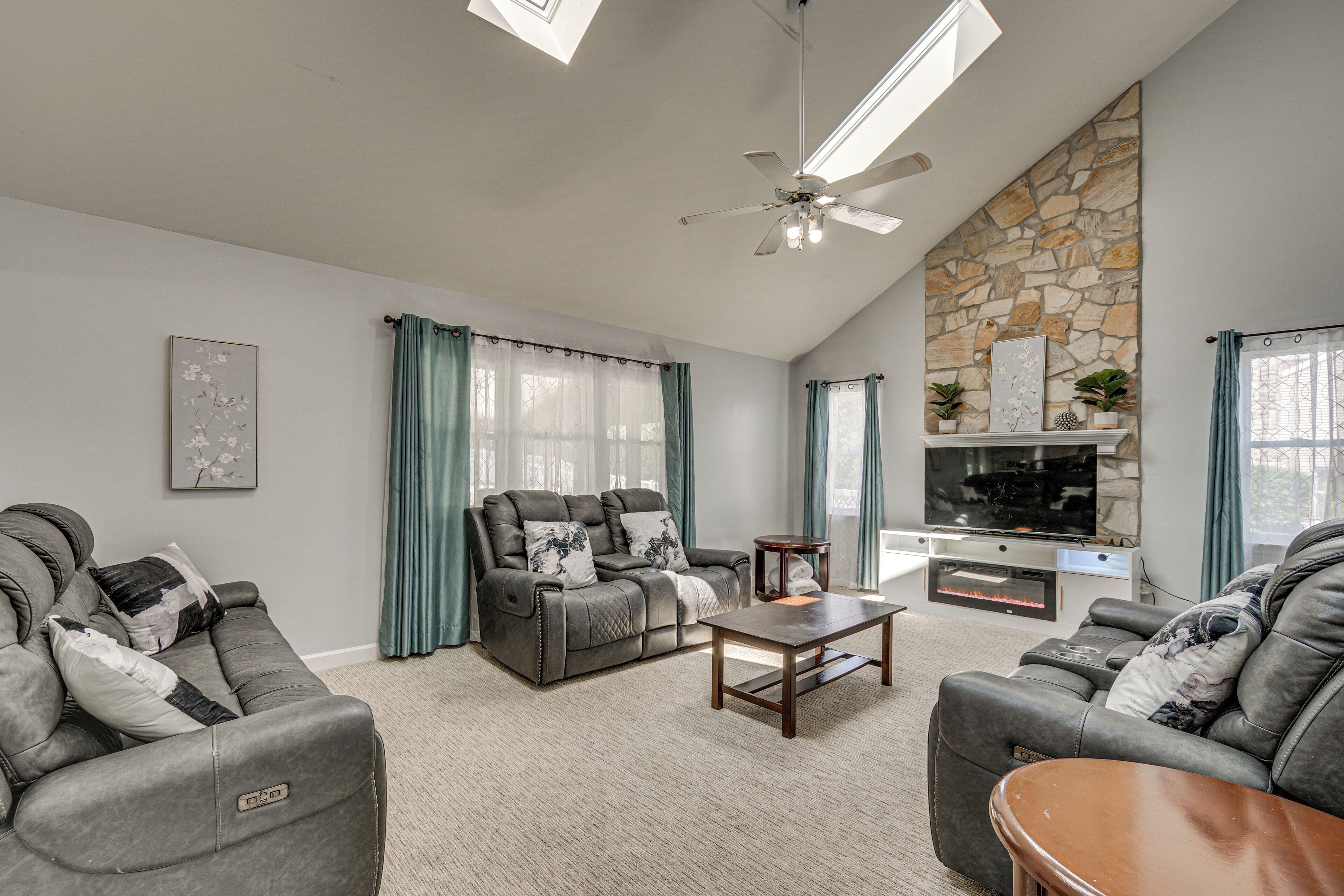 A living room with a stone accent wall, a fireplace, and a flat-screen TV.