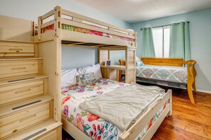 Una cama litera con estructura de madera, una mesita de noche y un aparador con cajones.