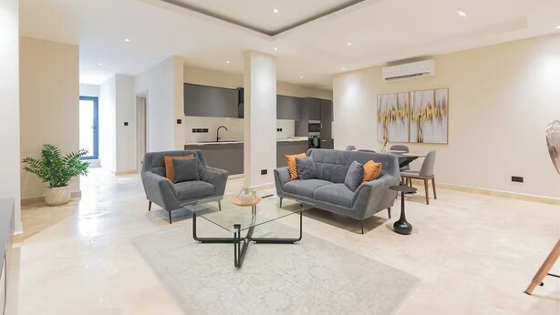 A spacious living area with two sofas, a coffee table, and a dining table with chairs. - Wentworth (Accra)
