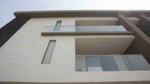 A modern building with a flat facade, large windows, and a balcony. - Wentworth (Accra)