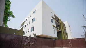 A modern building with a swimming pool, a gated entrance, and a clear sky. - Wentworth (Accra)