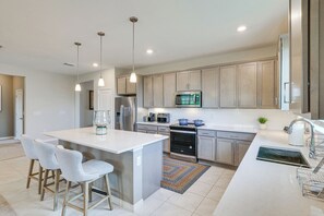 A modern kitchen with a central island, stainless steel appliances, and pendant lighting. - Home Office! Mascotte Family Escape Near Hospital (Mascotte)