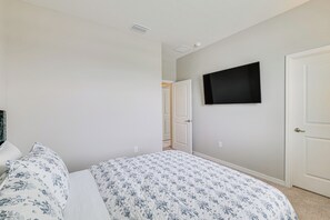 A bedroom with a bed, a television mounted on the wall, and a door leading to another room. - Home Office! Mascotte Family Escape Near Hospital (Mascotte)