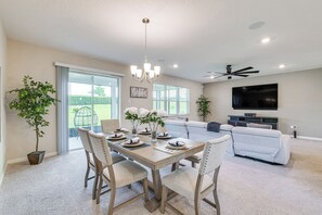 A dining area with a table set for four, a sofa, a television, and a ceiling fan. - Home Office! Mascotte Family Escape Near Hospital (Mascotte)