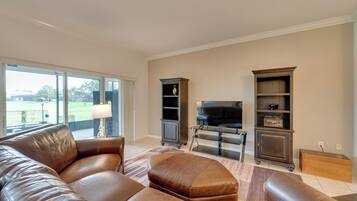 A living room with a leather sofa, a flat-screen TV, and a bookshelf.