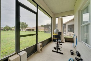 Un gimnasio con equipo de ejercicio, un ventanal y vista a una zona residencial.