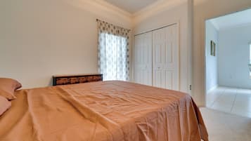 A bedroom with a bed, a dresser, a door, and a window with curtains.