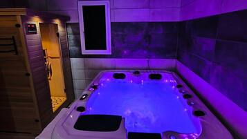Un jacuzzi con panel de control, rodeado de paredes de azulejos y una puerta de madera.