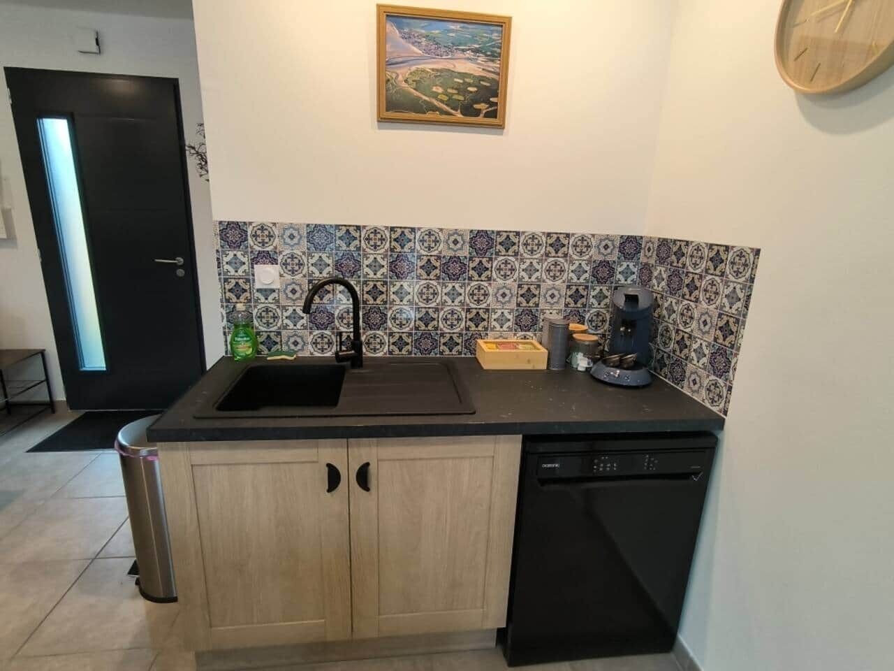 A compact kitchen with a black sink, wooden cabinets, and a dishwasher.